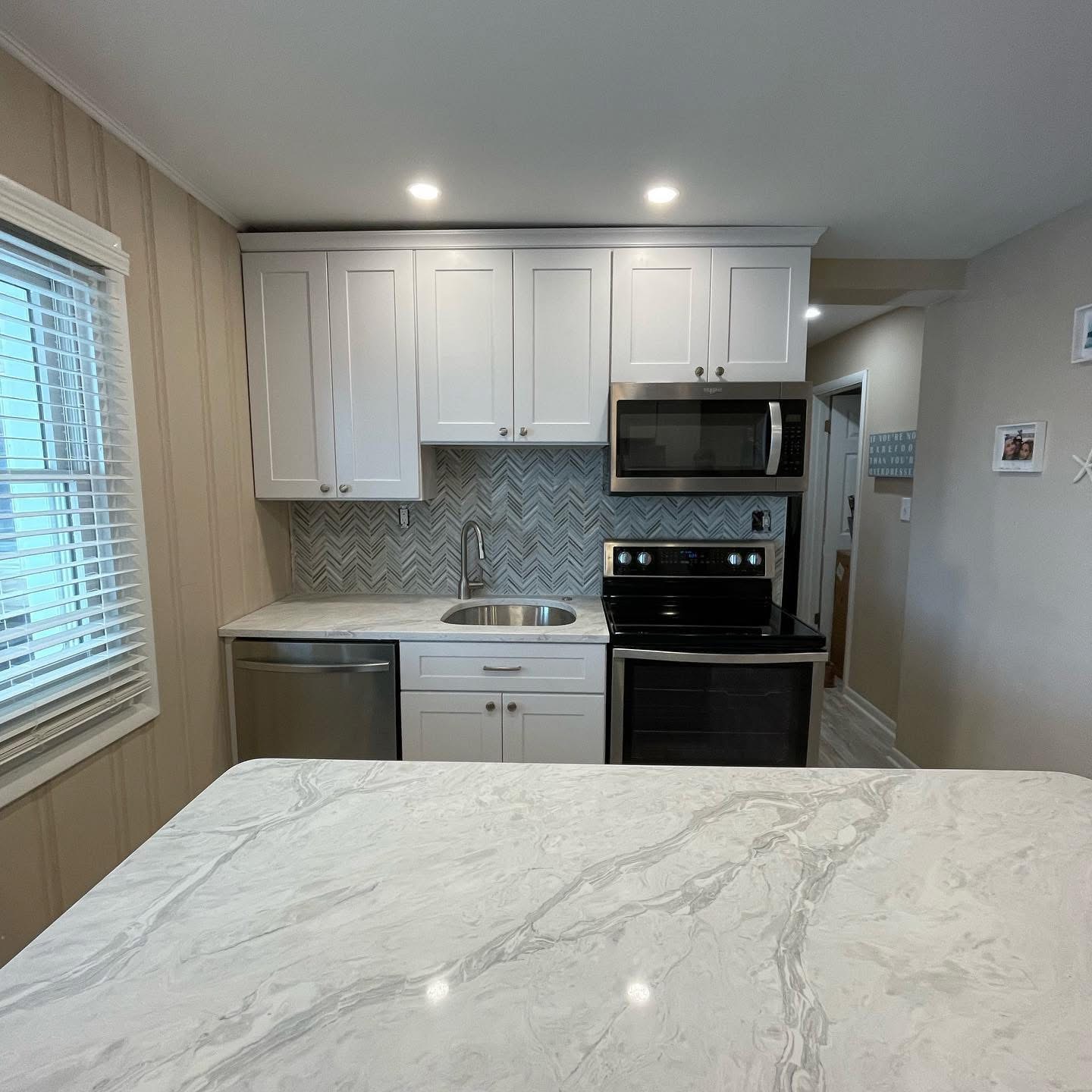 Compact kitchen remodel with white shaker cabinets and chevron tile backsplash