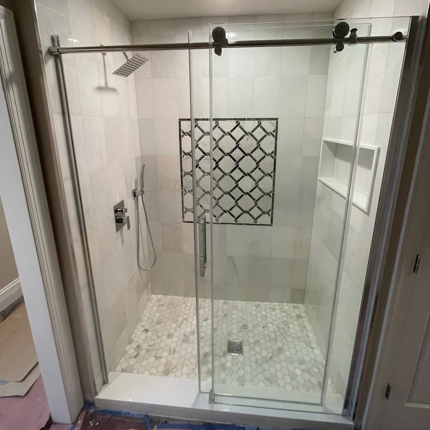 Walk-in shower with marble tile, mosaic accent panel and frameless glass doors